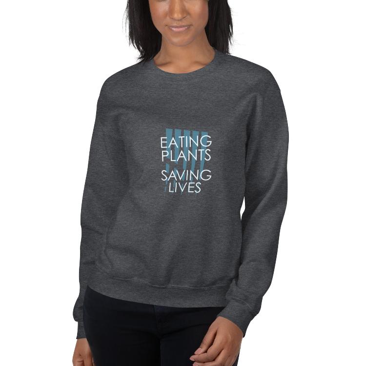 Cozy plant-based sweatshirt with the slogan 'Eating Plants, Saving Lives' on the front, featuring a label with human foot and animal paw prints, promoting animal welfare and a meat-free lifestyle