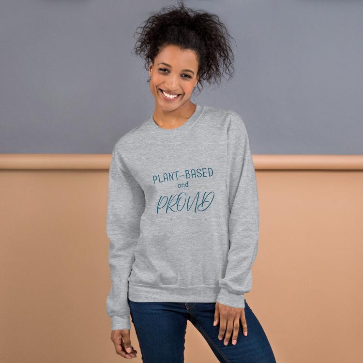 Cozy sweatshirt featuring the slogan "Plant-Based and Proud" on the front, with a human foot and animal paw print on the outside label, symbolizing harmony between humans and animals. Made from a blend of 50% cotton and 50% polyester, this pre-shrunk classic fit sweatshirt is ideal for colder months, promoting a plant-based lifestyle and raising awareness for animal welfare