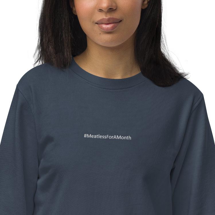 Organic unisex sweatshirt with #MeatlessForAMonth chest embroidery, human foot and animal paw design on right wrist, eco-friendly, made from organic cotton and recycled polyester, promotes plant-based lifestyle, animal rights, and sustainability